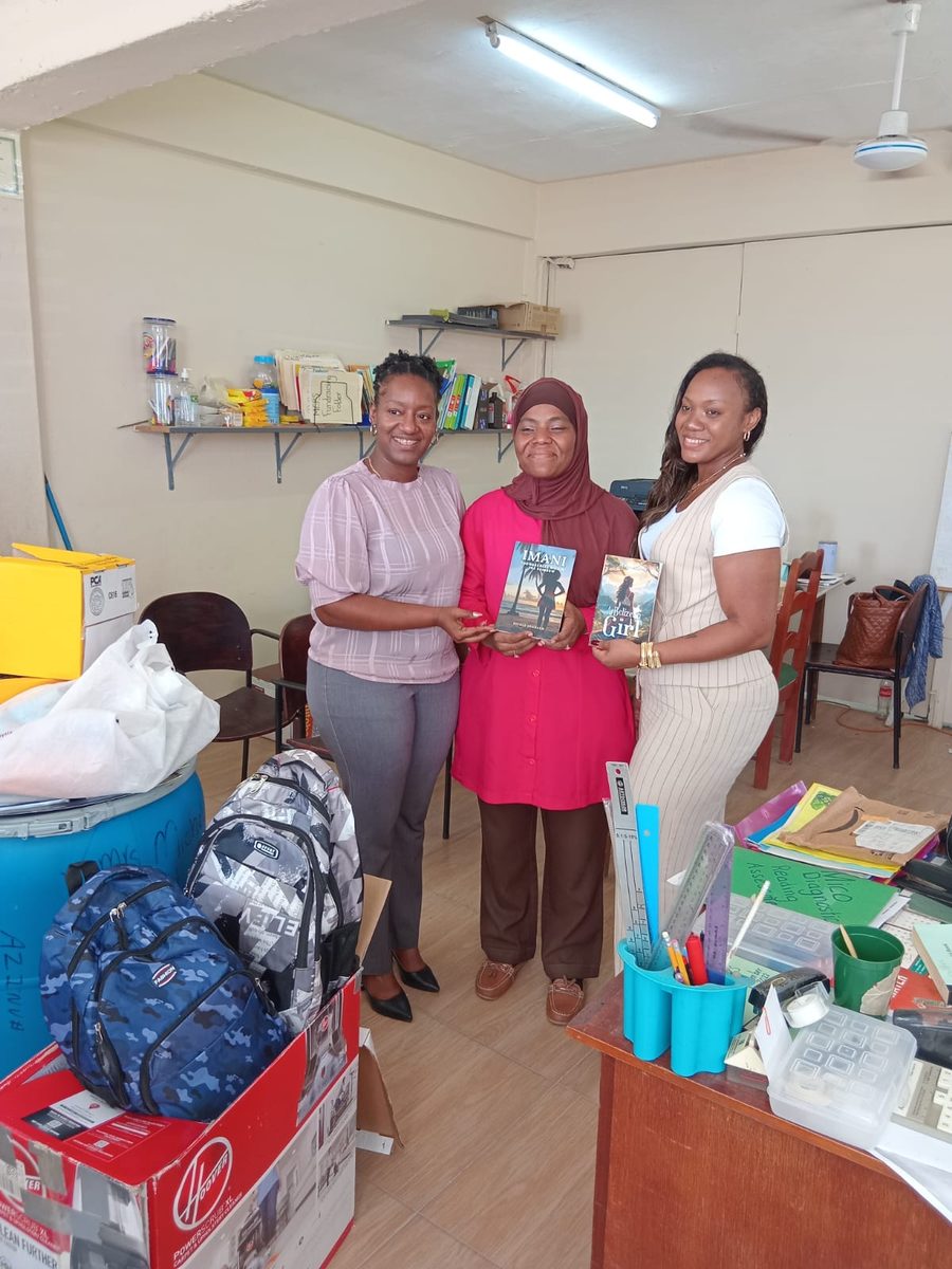 Nicole Johnson and school staff holding donated books including IMANI and A Belizean Girl